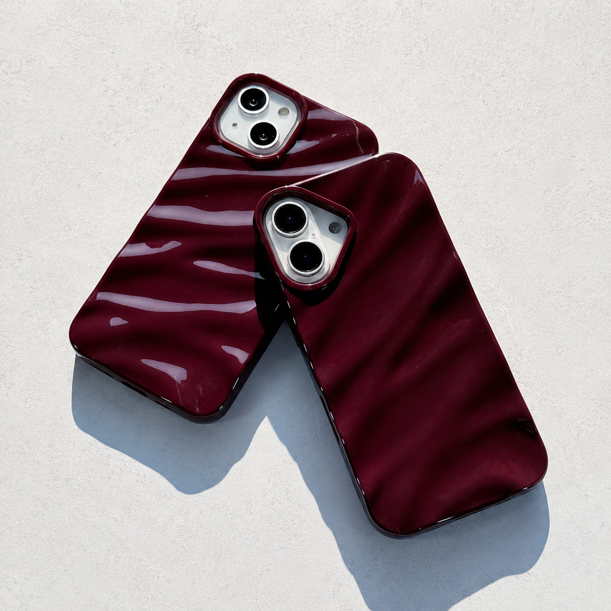 Two maroon phone cases on a light gray background